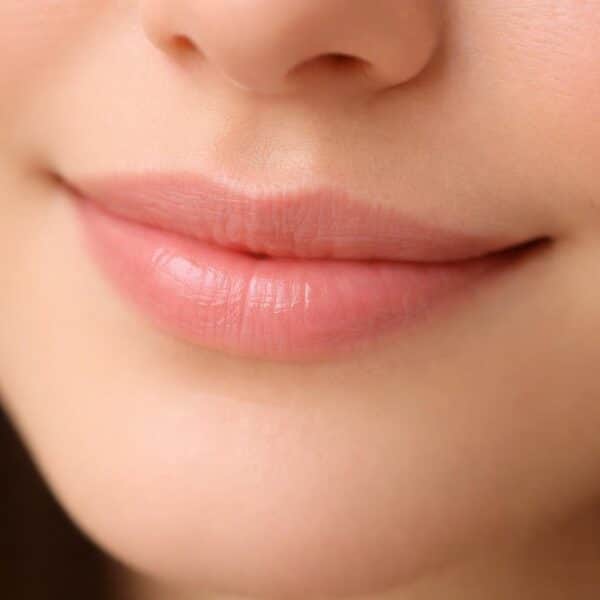 Close-up de uma boca com um sorriso sutil e delicado.