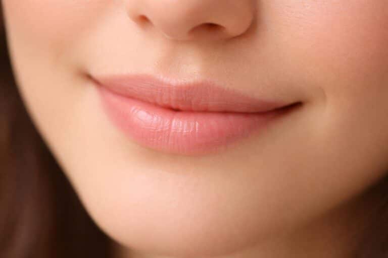 Close-up de uma boca com um sorriso sutil e delicado.