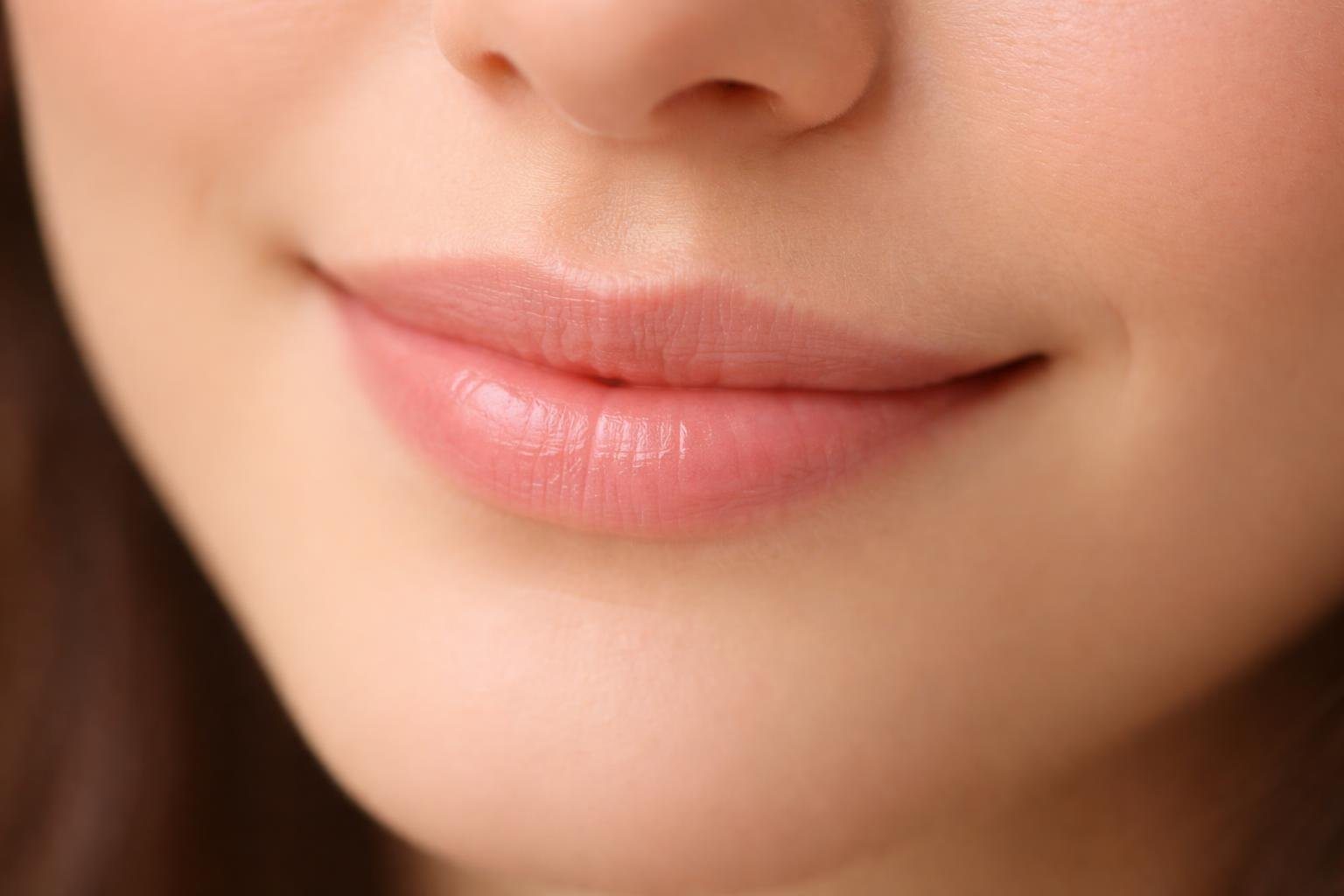 Close-up de uma boca com um sorriso sutil e delicado.